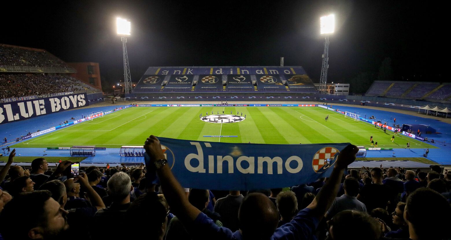 image depicting GNK Dinamo stadium with a fan holding a fan scarf
